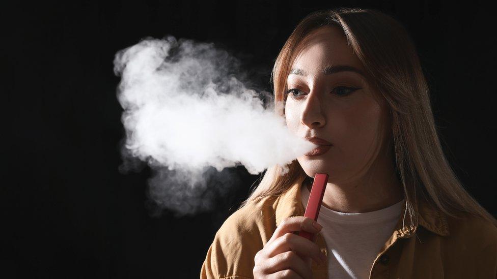 A young woman using a disposable vape