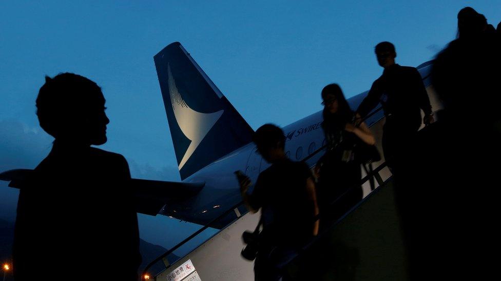 Passengers descending from a Cathay Pacific plane at night