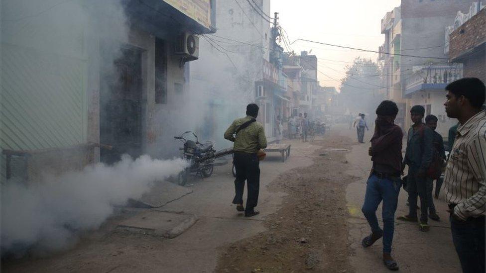 A municipal worker fumigates a residential area to prevent mosquitoes from breeding in Lucknow, India,