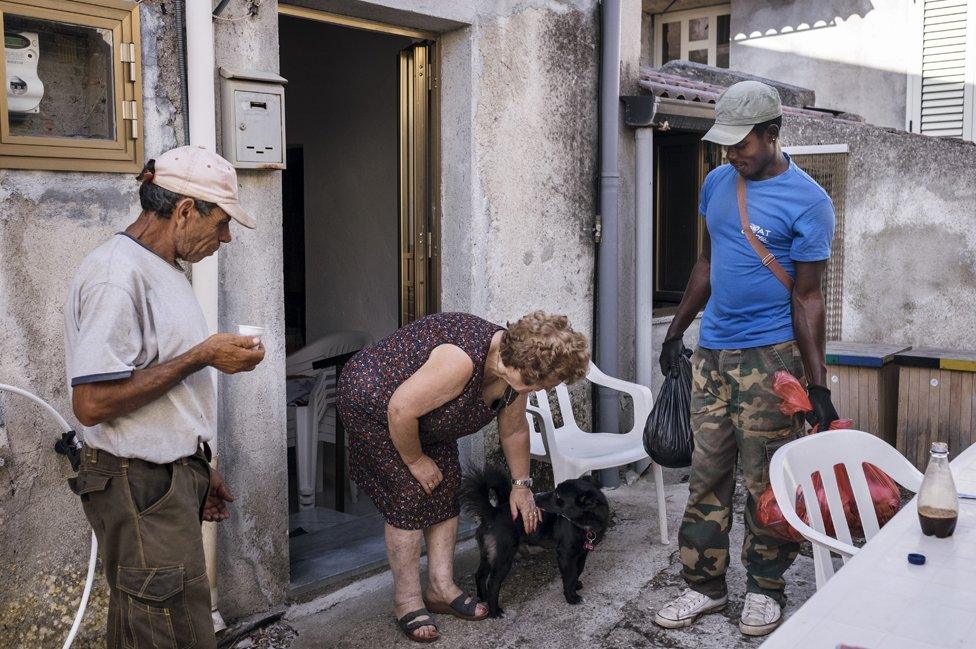 Biagio and Daniel chatting with a local woman during their door to door waste and recycling pickup.