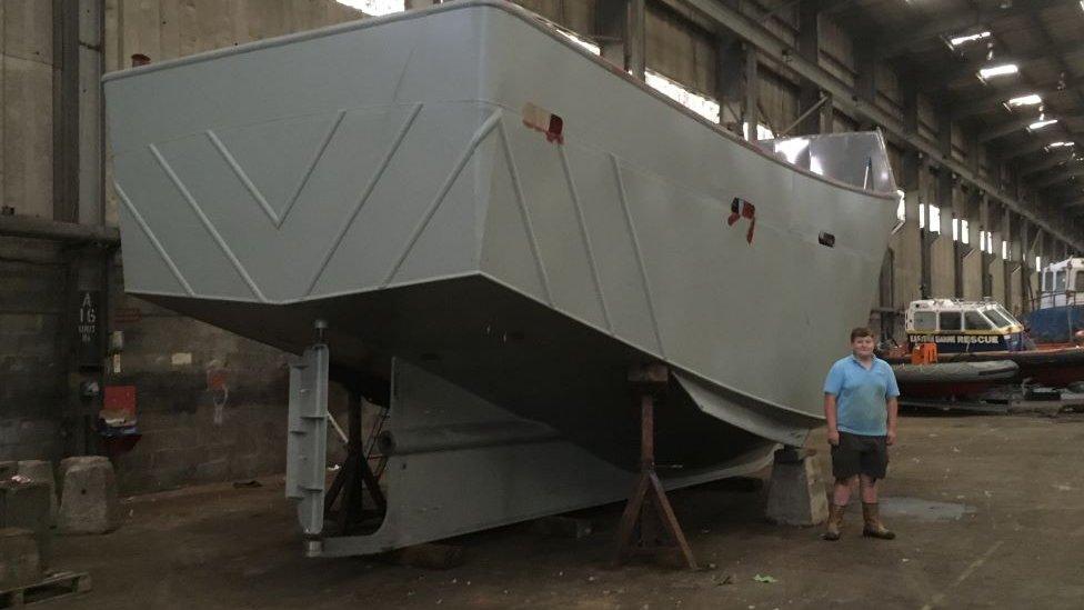 Alex Wightman, aged 15, standing next to the ship's hull