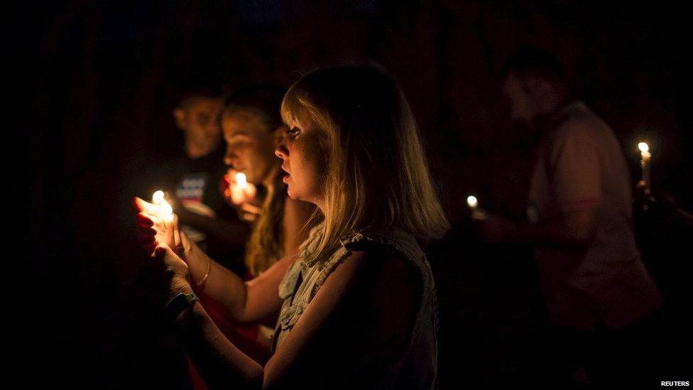 People hold candles as they walk to the beach of the Imperial Marhaba Hotel