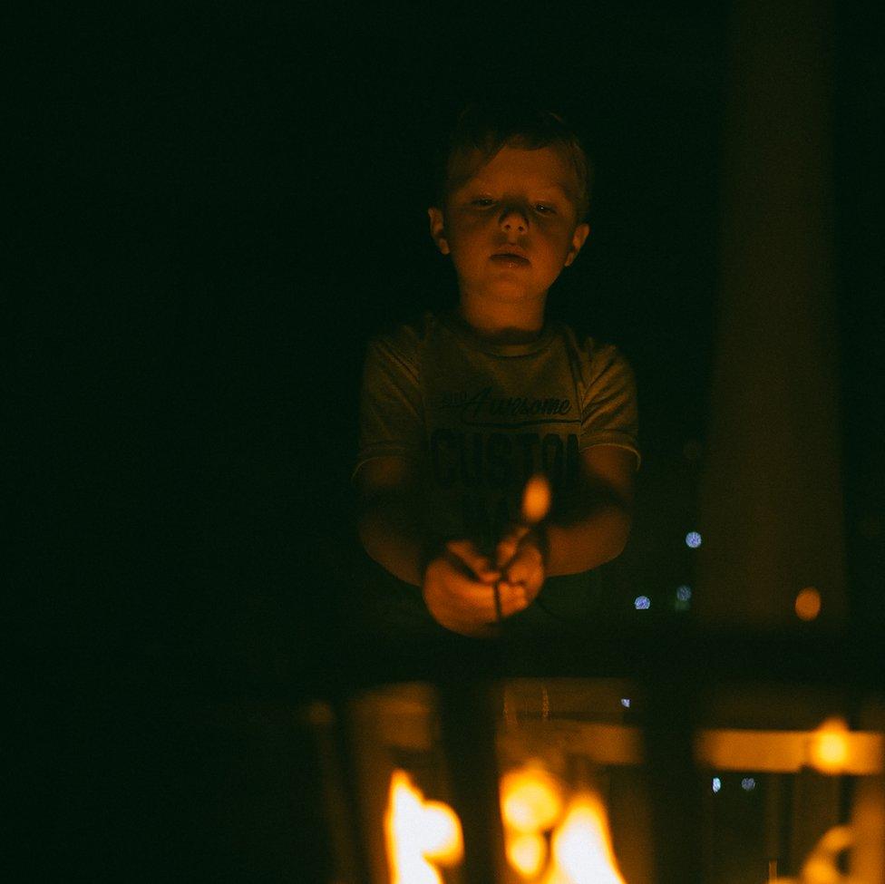 An image of a boy roasting food over a fire