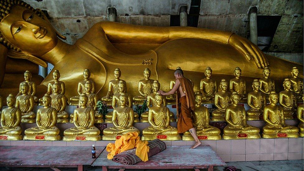 A monk cleaning a Buddha statue in Ipoh, Malaysia