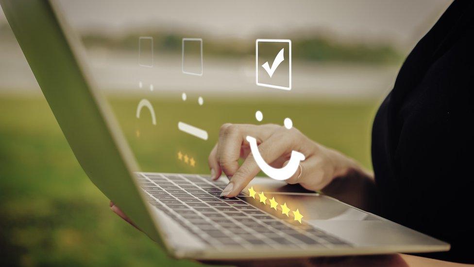 A woman writing a review on a laptop