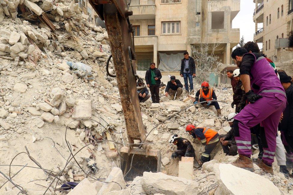 Rescue workers and civilians remove rubble from a collapsed building after a reported air strike on Idlib, Syria (15 March 2017)