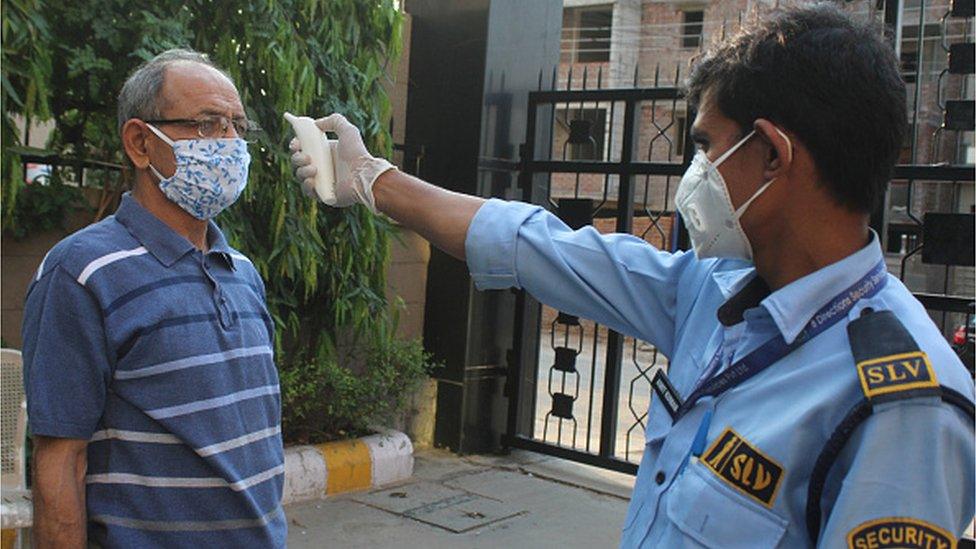 A resident undergoes thermal screening at an apartment complex during a nationwide lockdown over coronavirus in Gurugram