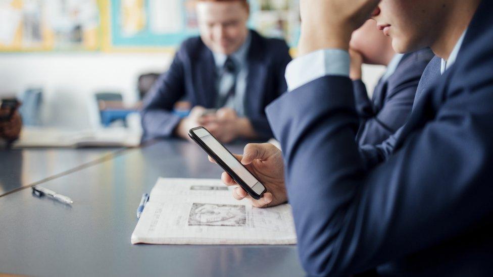 Boy using phone in a classroom