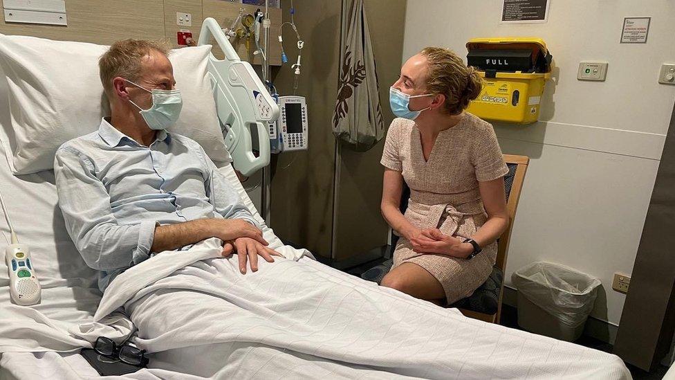 Richard Scolyer in a hospital bed with Georgina Long sitting beside him