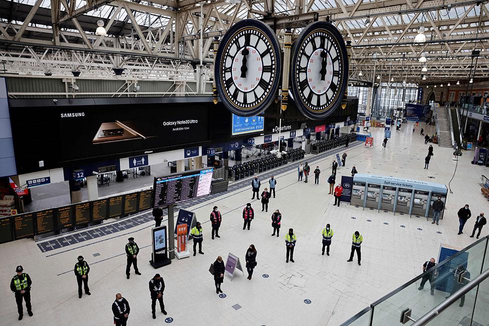 Commuters stand in the atrium of Waterloo station and observe a minute's silence