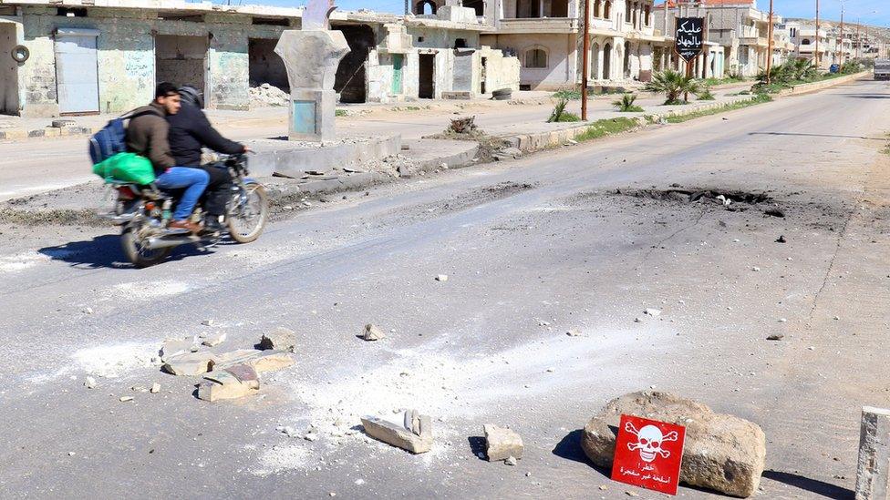 People drive past the site of a suspected chemical attack in Khan Sheikhoun, Syria (5 April 2017)