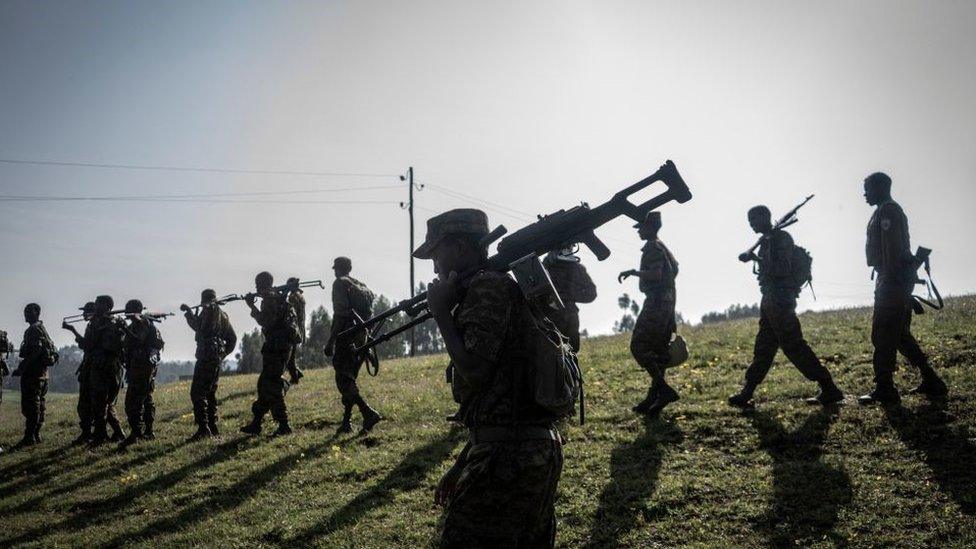 Photo of soldiers walking in a field carrying large weapons