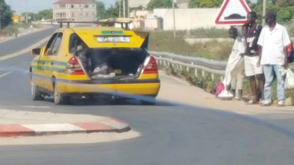 A person getting into the boot of a taxi in The Gambia