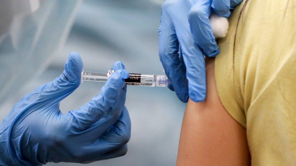 A nurse administers a vaccination shot to a woman - library picture