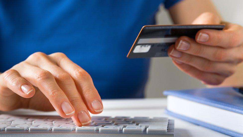 Stock image of person using computer keyboard while holding a credit card