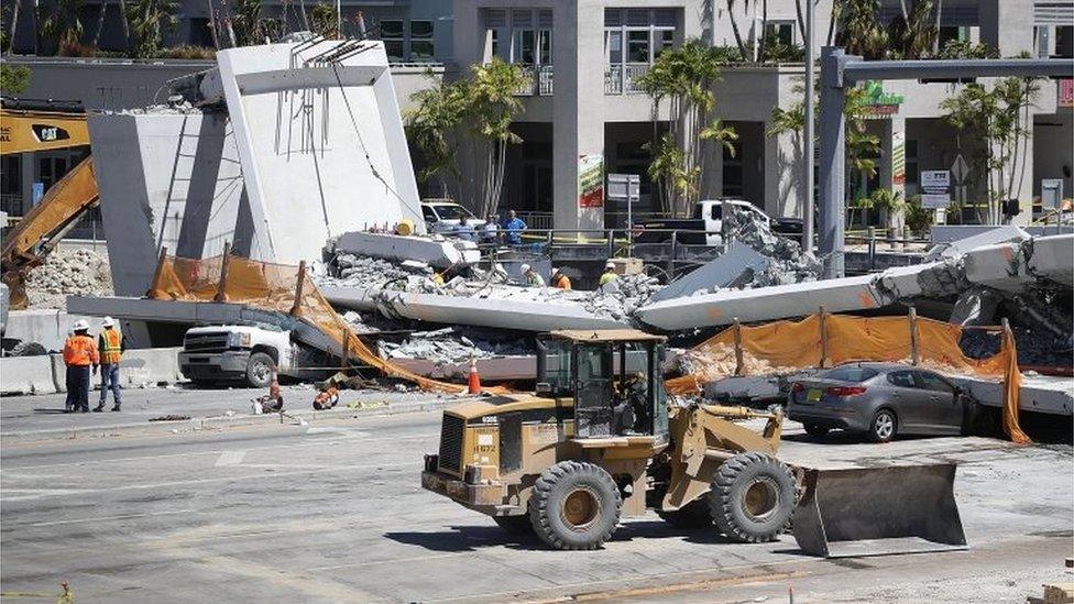 Law enforcement and members of the National Transportation Safety Board investigate the scene where a pedestrian bridge collapsed a few days after it was built in Miami, Florida.