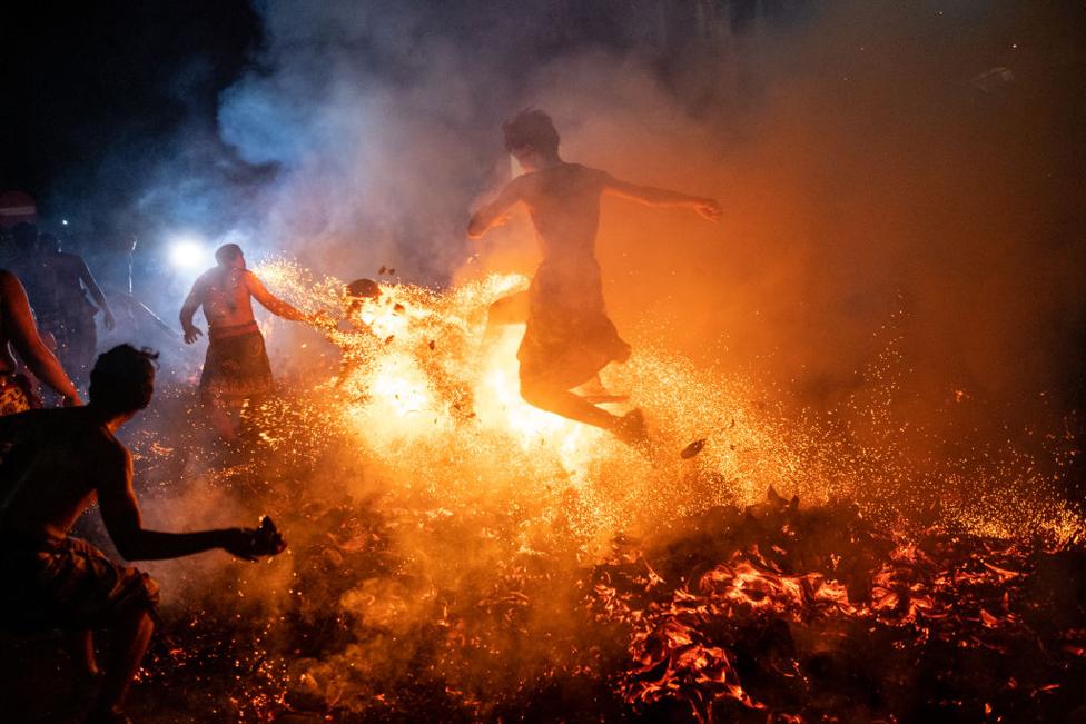 Balinese man kicks burnt coconut husks during the fire fight ritual called Mesabatan Api on March 21, 2023 in Gianyar, Bali, Indonesia.