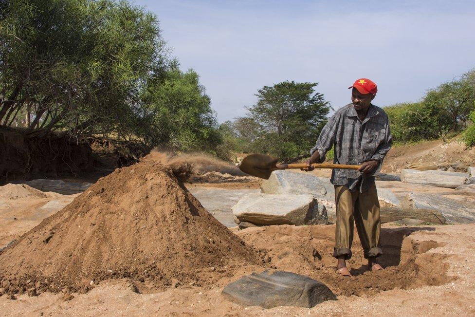 Sand harvester Richard Mutinda, 40, shovels sand into a big pile to be collected by trucks later that day. 100 tonnes of sand can be taken a day from this stretch of the Nthange River alone. There are 15 - 20 harvesting sites on this river.