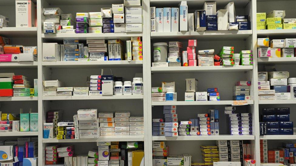 Pharmacy shelves piled with prescription drugs.