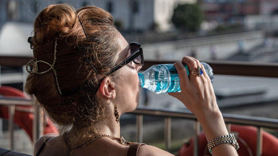 A woman seen drinking water in an open area of the ferry. On a summer day, the temperature in Istanbul soared to a sweltering 40 degrees Celsius