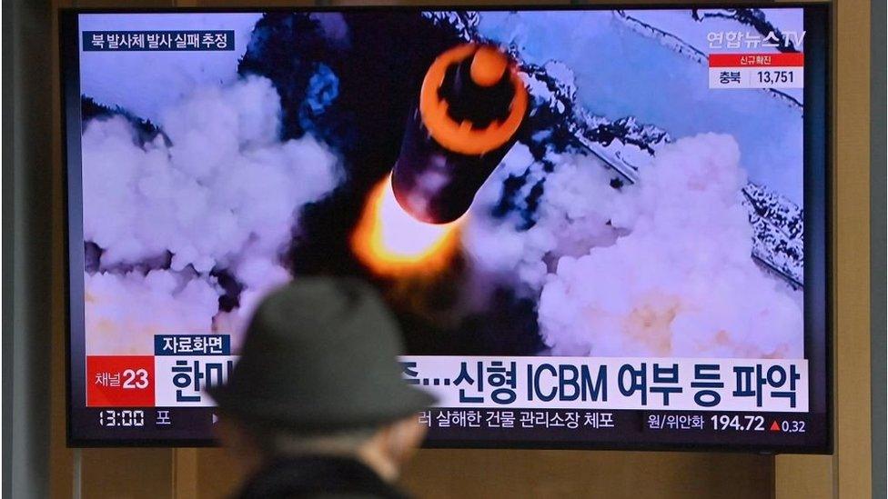 People watch a television screen showing a news broadcast with file footage of a North Korean missile test, at a railway station in Seoul on March 16, 2022