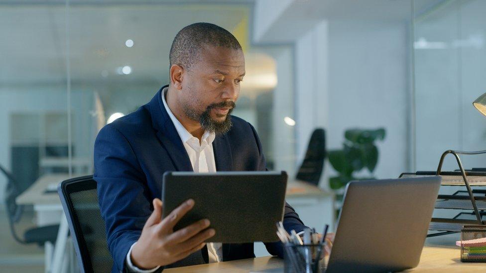 A man looking at a screen and tablet