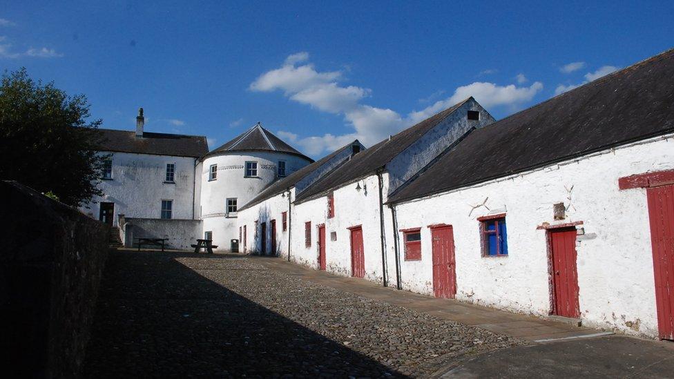 A wide shot showing Bellaghy Bawn, which is a collection of small white buildings