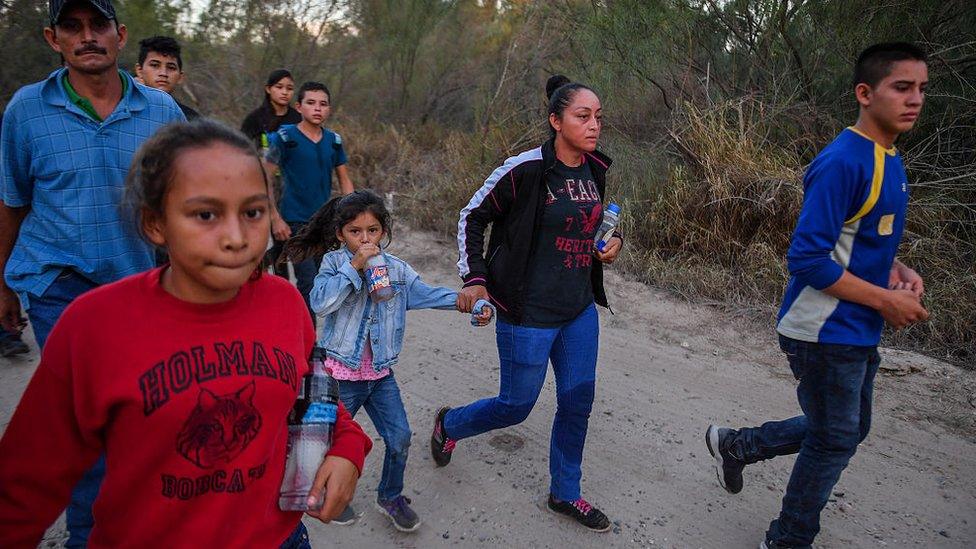 Border crossers quickly walk away after being discovered entering into the United States by the U.S. Border Patrol. The group had just rafted across the Rio Grande River in McAllen, Texas.