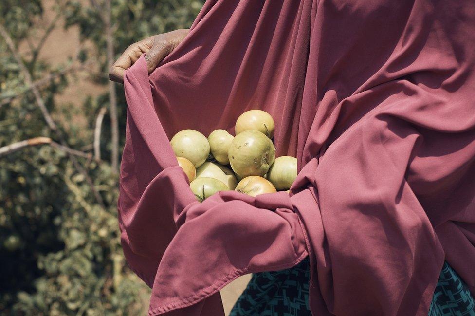 A woman holds a collection of fruit