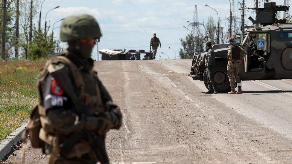 Service members of pro-Russian troops stand guard in Mariupol, Ukraine