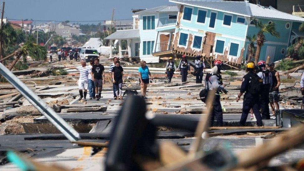 Mexico Beach residents walk down a street on Thursday