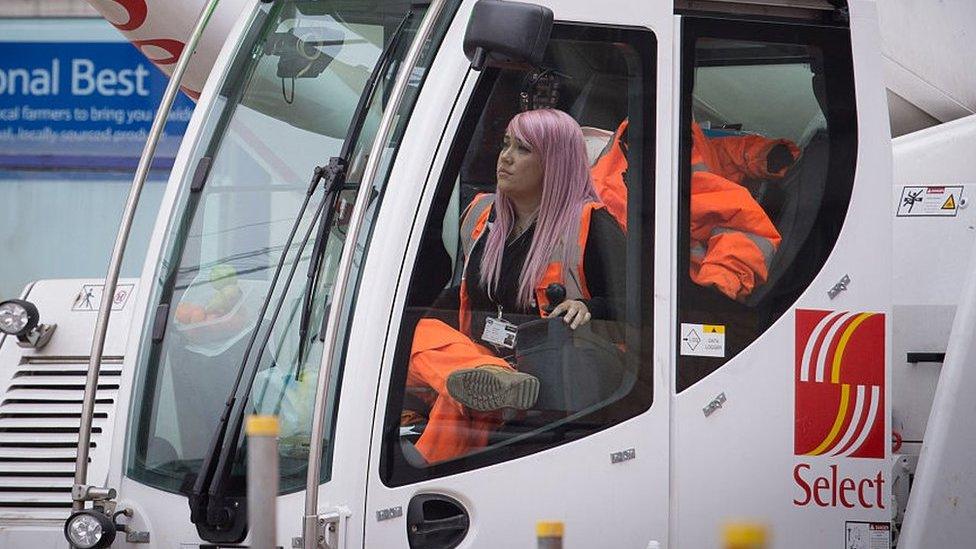 Young female apprentice operating a crane.