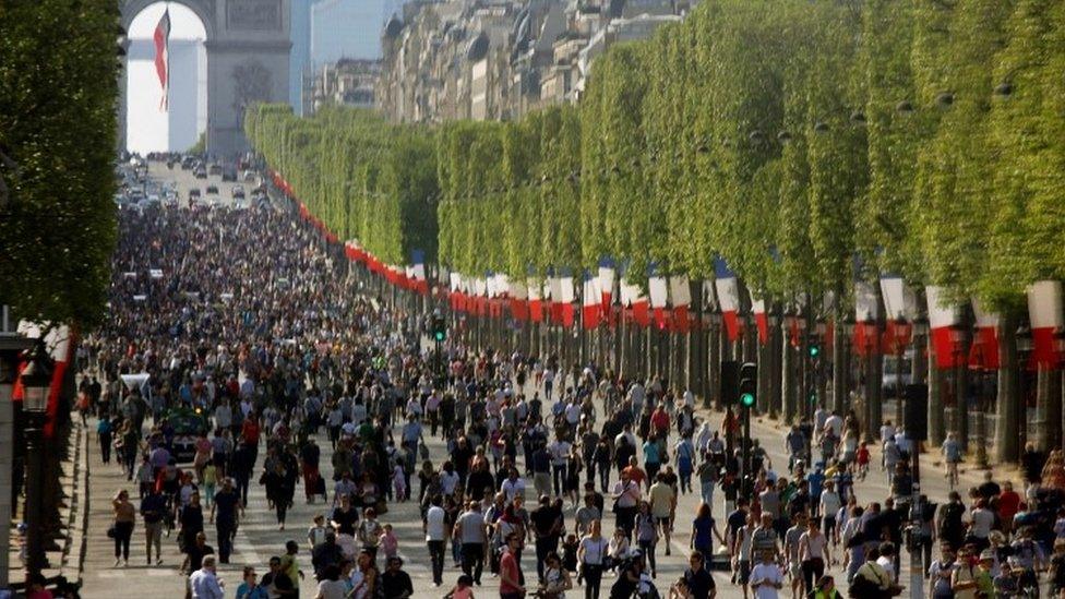 People walk on the car-free Champs-Elysees avenue in Paris (08 May 2016)