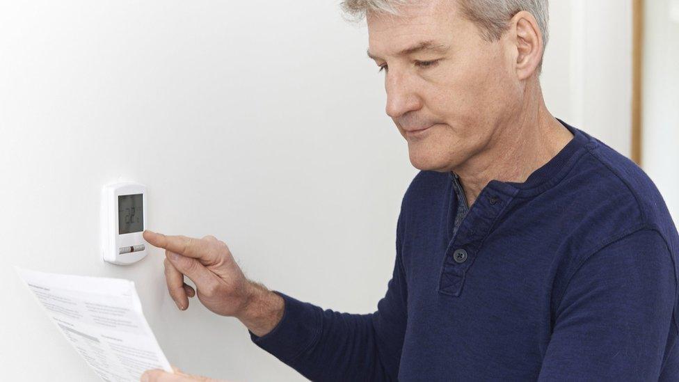 man adjusts thermostat