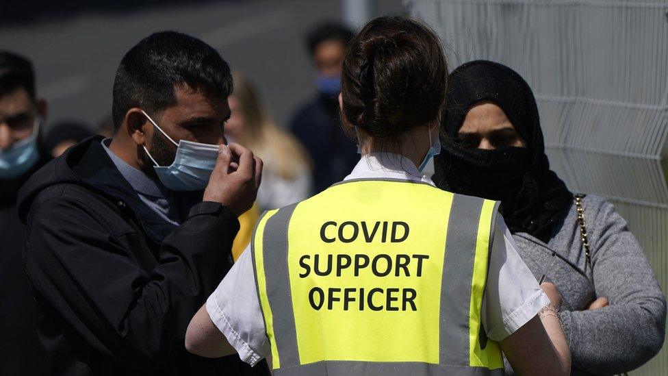 A Covid support officer talking to people in a vaccination queue in an area where the Indian variant was found