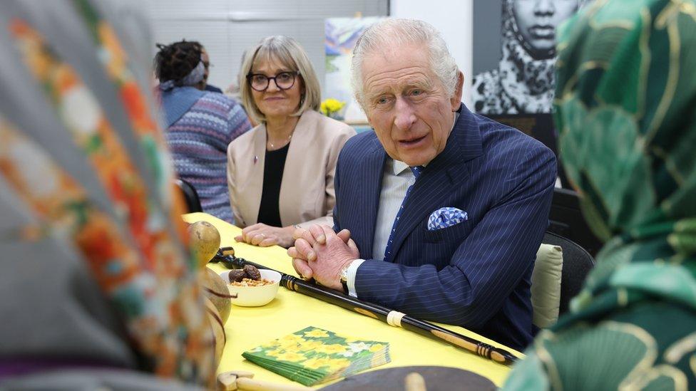 The King speaks to two women in headscarves at the event.