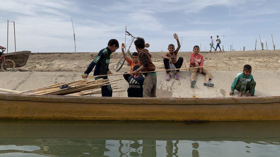 Children on a waterway bank smiling and waving