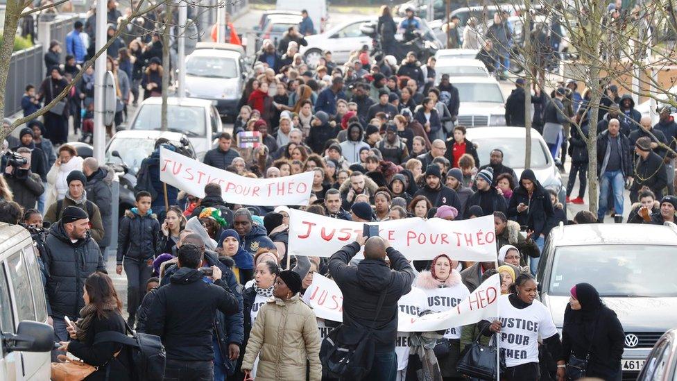 People hold a sign reading "Justice for Theo" during a protest on 6 February 2017 in Aulnay-sous-Bois, northern Paris, a day after a French police officer was charged with the rape of a youth who was severely injured after allegedly being sodomised with a baton