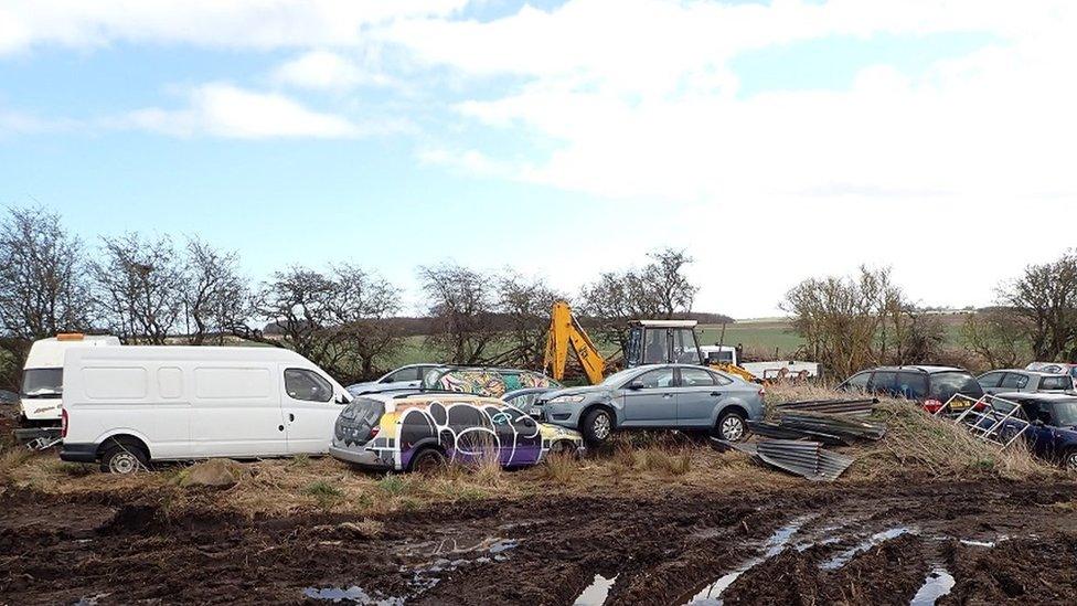 Vans and cars in a field