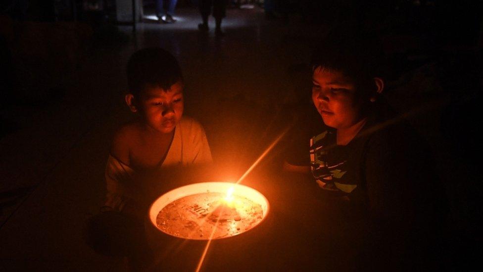 Two boys in a power-cut-affected evacuation centre ride out the storm