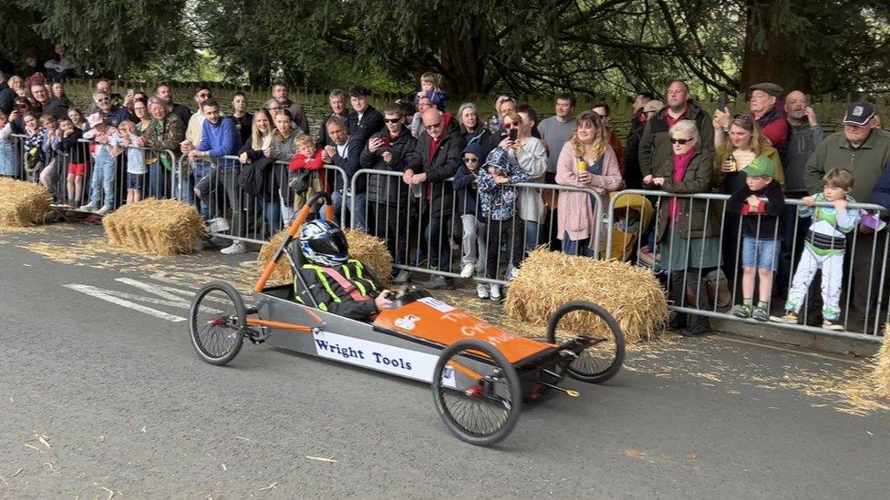 Spectators watching an orange go-kart