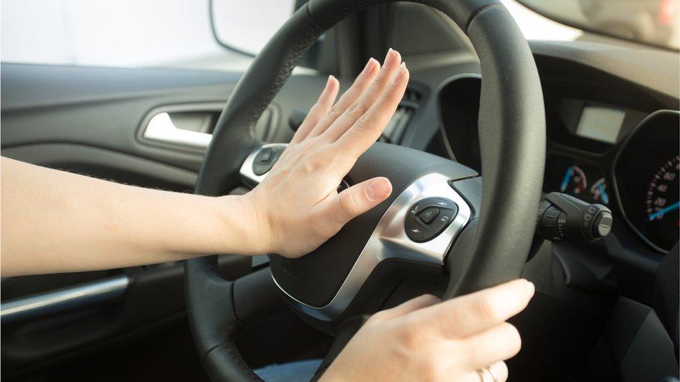 Woman honking horn in car