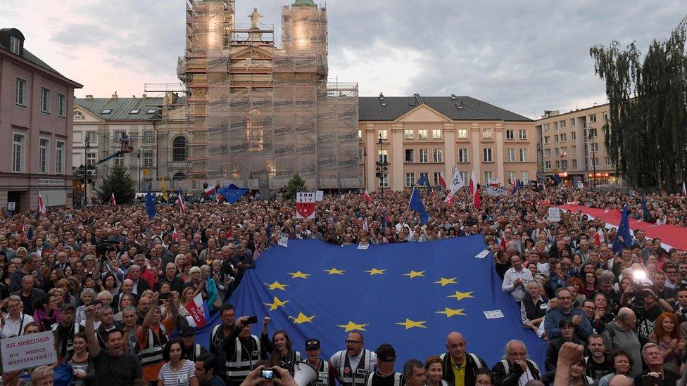 Image shows people demonstrating in support of the Supreme Court judges in front of the Supreme Court building in Warsaw, Poland, in July 2018