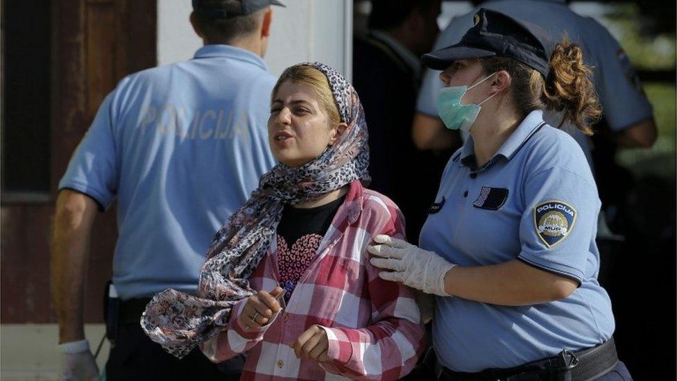 A Croatian policewoman directs a migrant crossing from Serbia after registration in Tovarnik.