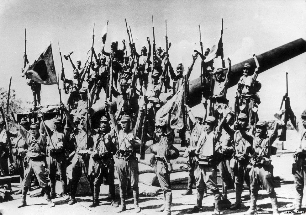 1942: Japanese soldiers celebrate after capturing an American gun emplacement in the Bataan province of the Philippines