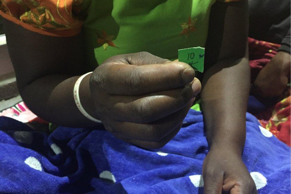 A woman holding a piece of paper for her number in the queue