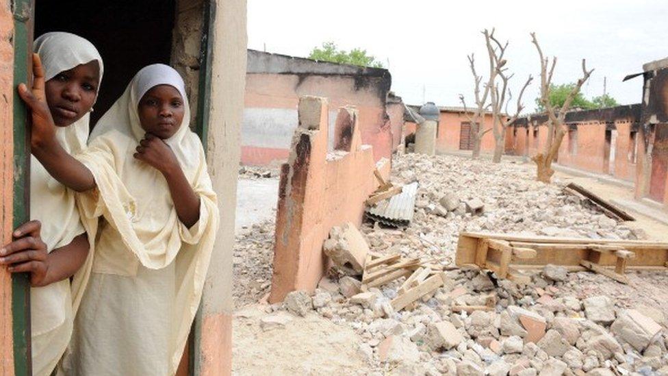 Female students stand in a burnt classroom at Maiduguri Experimental School in Maiduguri, north-eastern Nigeria, after it was attacked by Boko Haram militants to keep children away from education (12 May 2012)