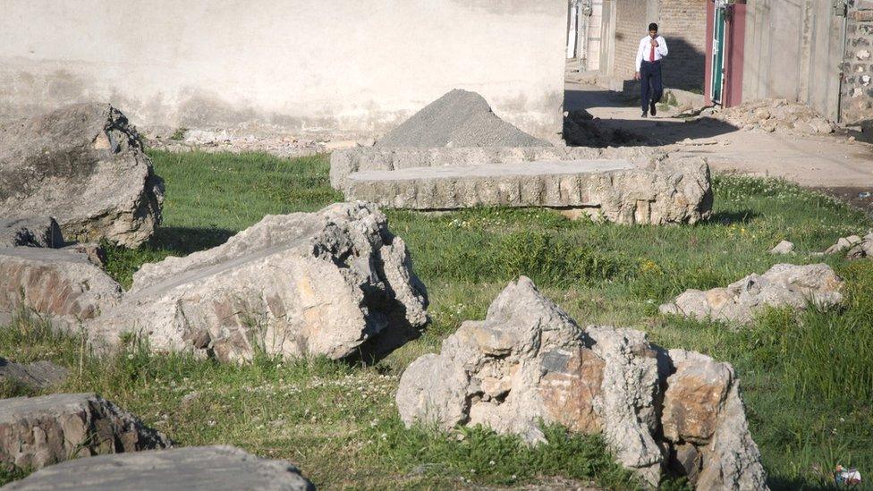 Fragments of concrete blocks remain on the razed compound