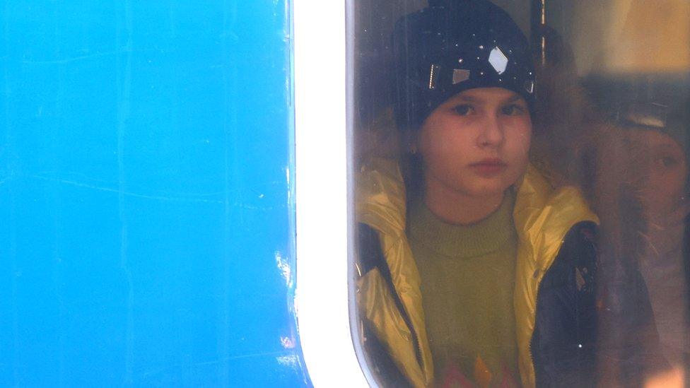 A young Ukrainian refugee looks out from the window of a train