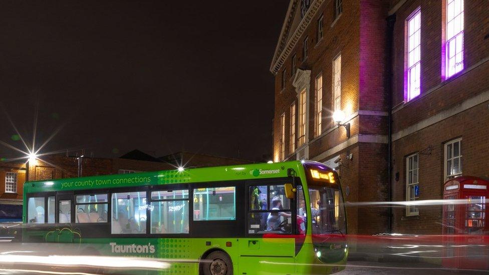 Green bus photographed at night